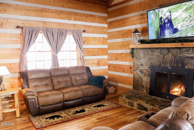 living area featuring a stone fireplace, wooden walls, and wood finished floors
