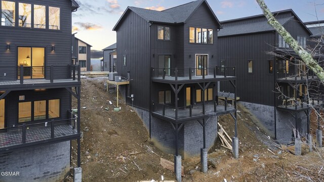 back house at dusk with a balcony and cooling unit