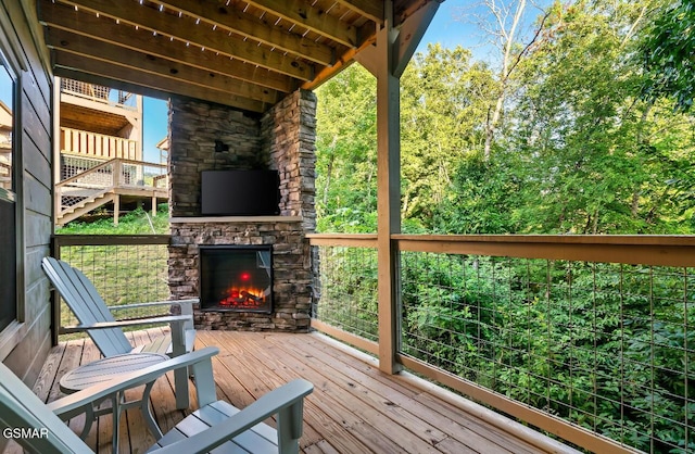 wooden terrace featuring an outdoor stone fireplace