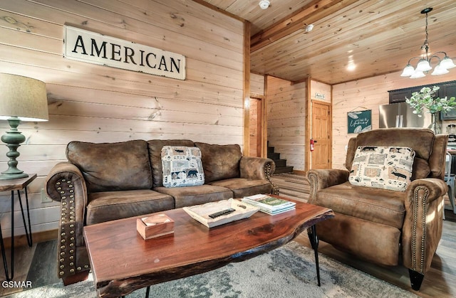 living room with a notable chandelier, wood walls, and wooden ceiling