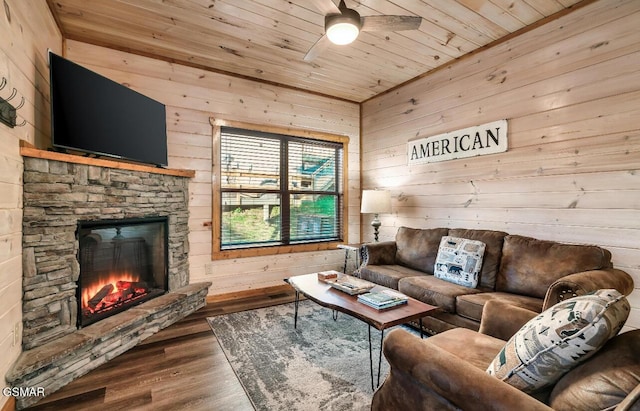 living room featuring a stone fireplace, wooden walls, wooden ceiling, and wood-type flooring