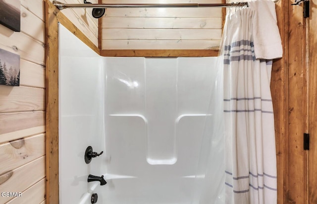 bathroom featuring shower / bath combo and wooden walls