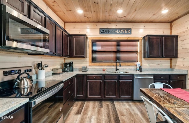 kitchen with wood walls, sink, wood ceiling, and appliances with stainless steel finishes