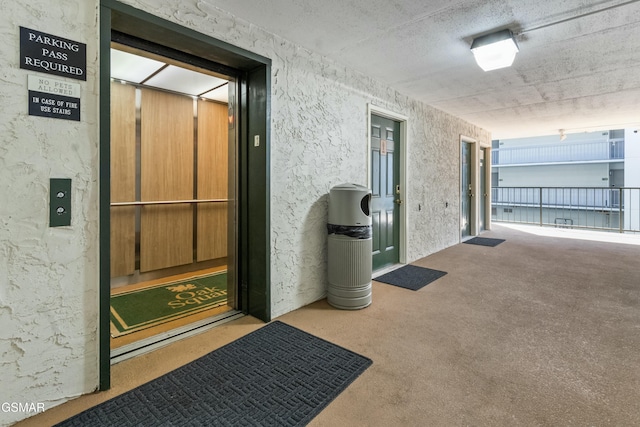 hallway with elevator and carpet