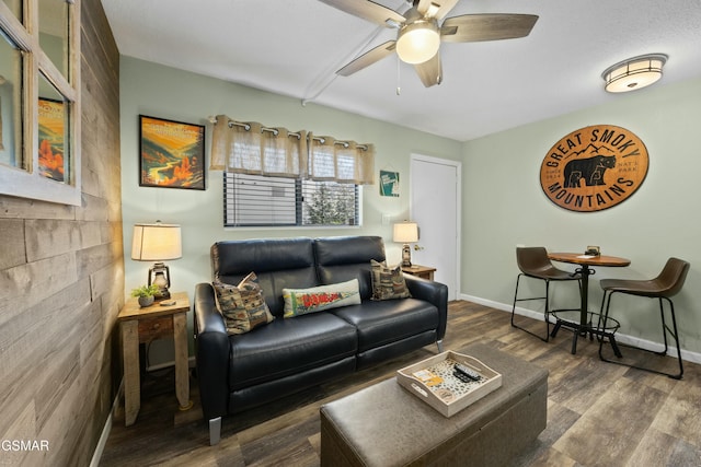 living room with ceiling fan, baseboards, and wood finished floors