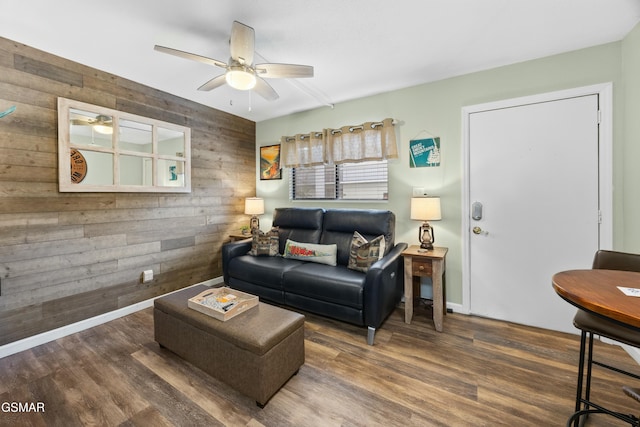 living room with wood walls, ceiling fan, baseboards, and wood finished floors