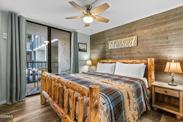 bedroom with wood walls, floor to ceiling windows, access to outside, hardwood / wood-style flooring, and ceiling fan