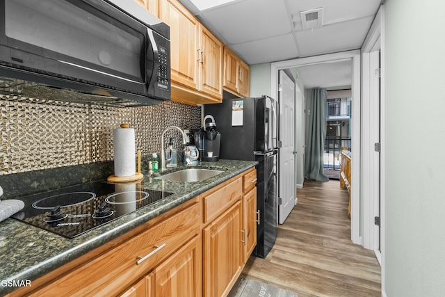 kitchen with a drop ceiling, sink, tasteful backsplash, light hardwood / wood-style floors, and black appliances