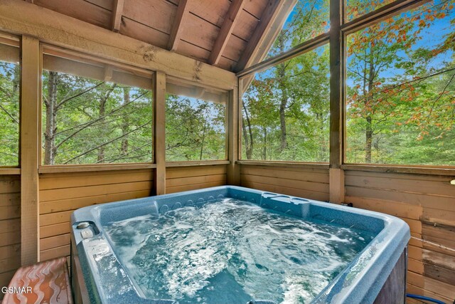 unfurnished sunroom featuring a jacuzzi, vaulted ceiling with beams, a healthy amount of sunlight, and wood ceiling