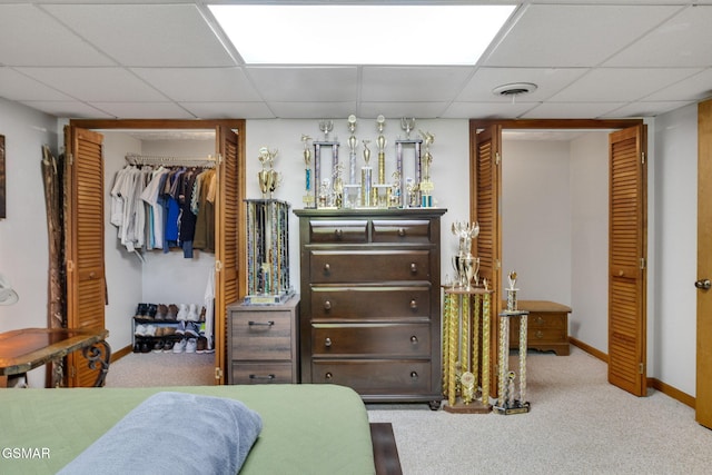 bedroom featuring carpet floors, baseboards, a drop ceiling, and visible vents