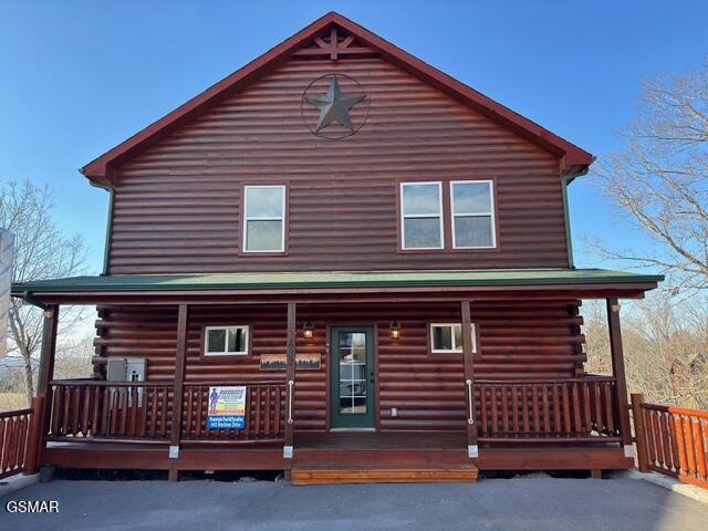 rear view of property featuring log siding and a porch