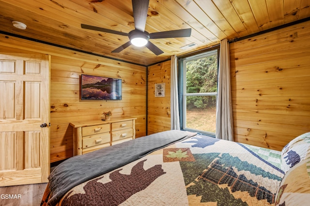 bedroom with wooden walls, hardwood / wood-style floors, ceiling fan, and wooden ceiling