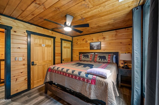 bedroom with ceiling fan, wood walls, dark hardwood / wood-style flooring, and wooden ceiling