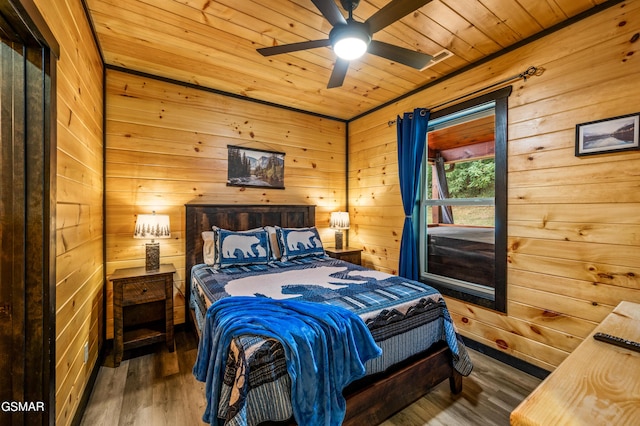 bedroom featuring wooden walls, dark hardwood / wood-style floors, ceiling fan, and wooden ceiling