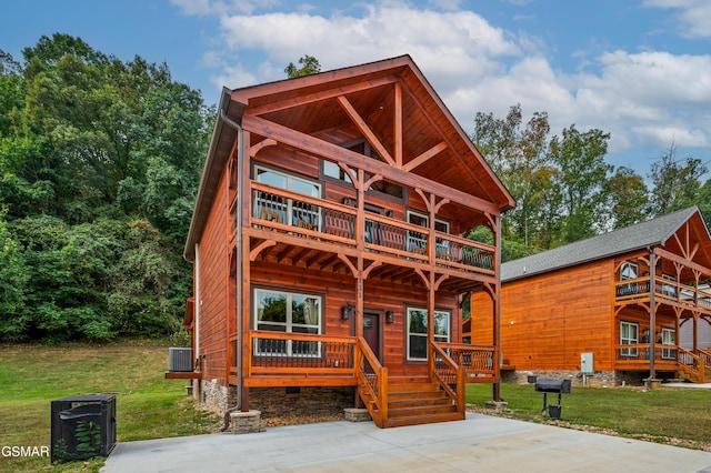 log home featuring a balcony and a front lawn