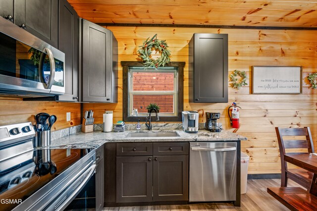 kitchen with light stone countertops, appliances with stainless steel finishes, wooden ceiling, and sink