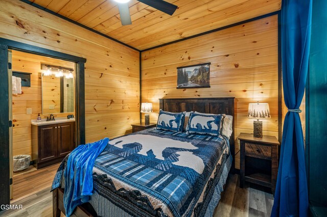 bedroom with ceiling fan, wooden walls, hardwood / wood-style flooring, wooden ceiling, and connected bathroom