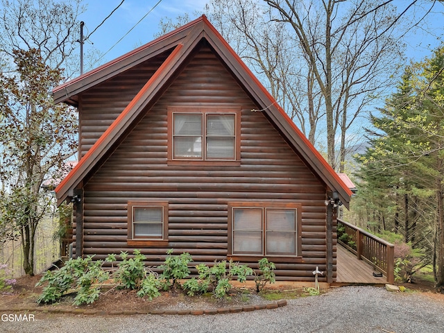 view of side of home with a wooden deck and log siding