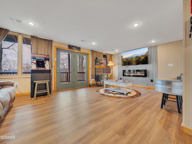 living room featuring recessed lighting, a glass covered fireplace, light wood-style floors, and visible vents
