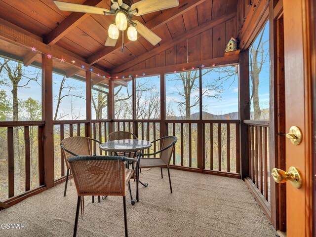 sunroom with beamed ceiling, a ceiling fan, and outdoor dining area