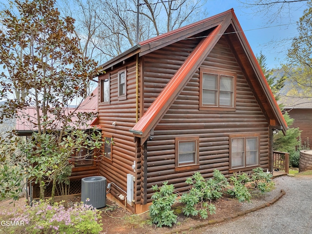 view of side of property with log exterior, cooling unit, and metal roof