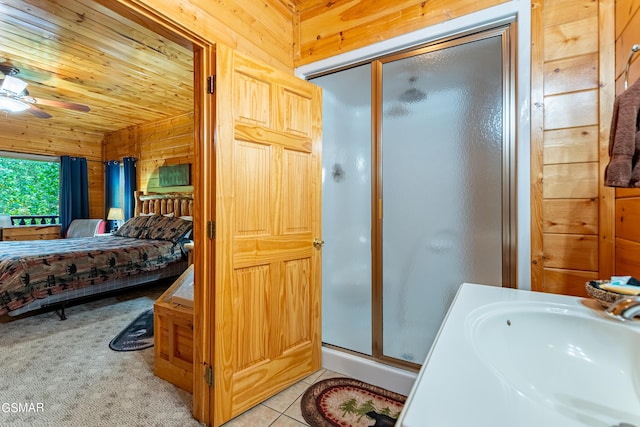 bathroom featuring ceiling fan, sink, wood walls, wood ceiling, and a shower with shower door