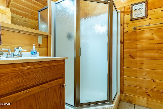 bathroom with tile patterned flooring, vanity, a shower with door, and wood walls