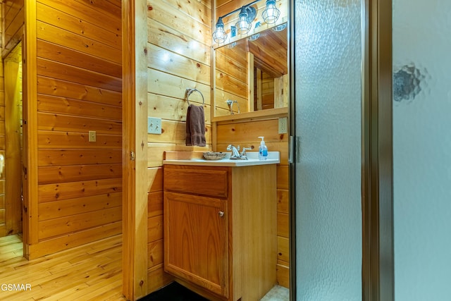 bathroom featuring wood walls, vanity, and an enclosed shower