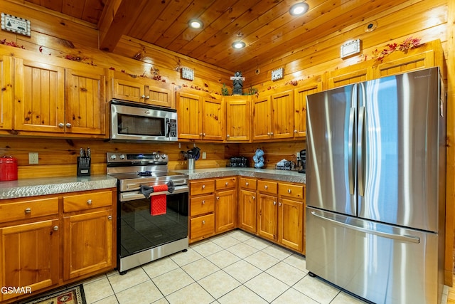 kitchen with wooden ceiling, beamed ceiling, wood walls, light tile patterned flooring, and appliances with stainless steel finishes