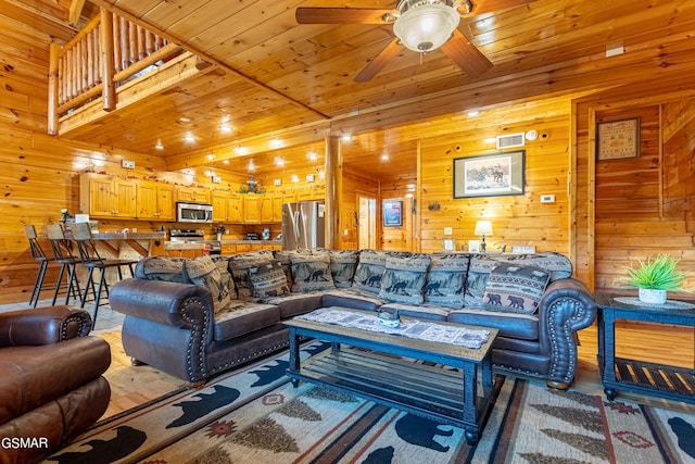 living room featuring ceiling fan, wooden ceiling, and wood walls