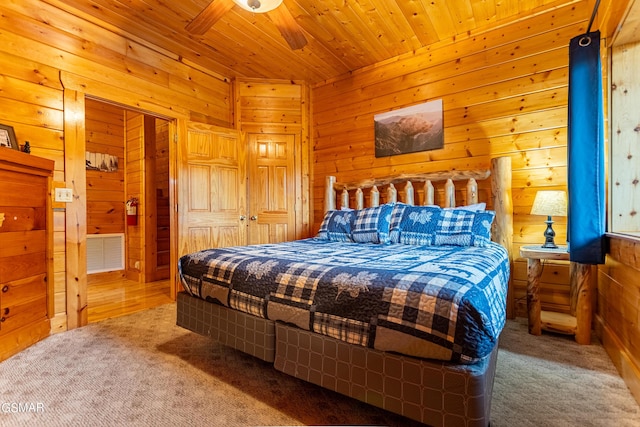 carpeted bedroom featuring ceiling fan, wooden ceiling, and wood walls