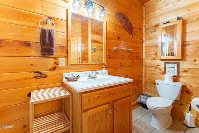 bathroom with toilet, vanity, tile patterned floors, and wooden walls