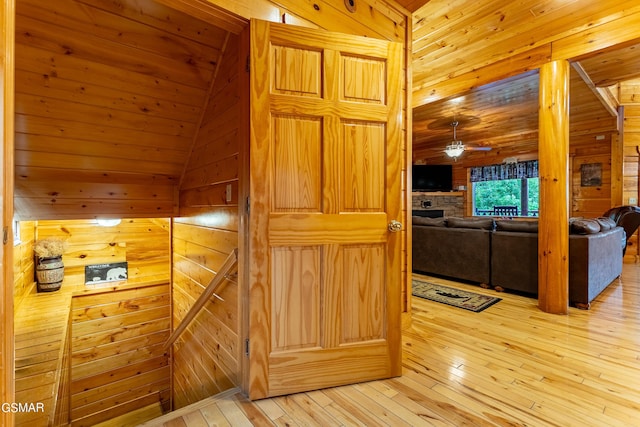 hall with wooden walls, hardwood / wood-style floors, and vaulted ceiling