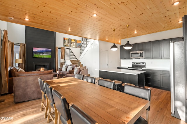 dining room with stairway, wood ceiling, a fireplace, light wood-style floors, and recessed lighting