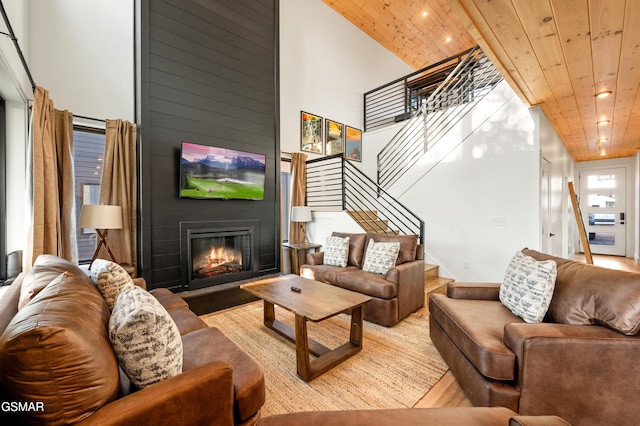 living room featuring wood ceiling, a towering ceiling, stairway, a large fireplace, and recessed lighting