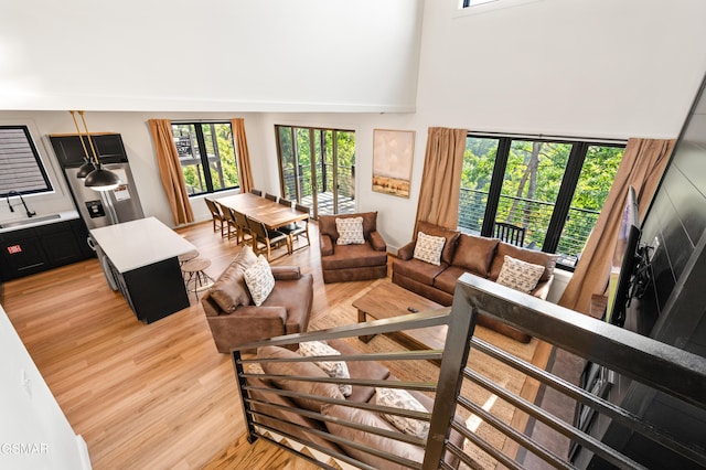 living area featuring healthy amount of natural light, light wood-style floors, and a high ceiling