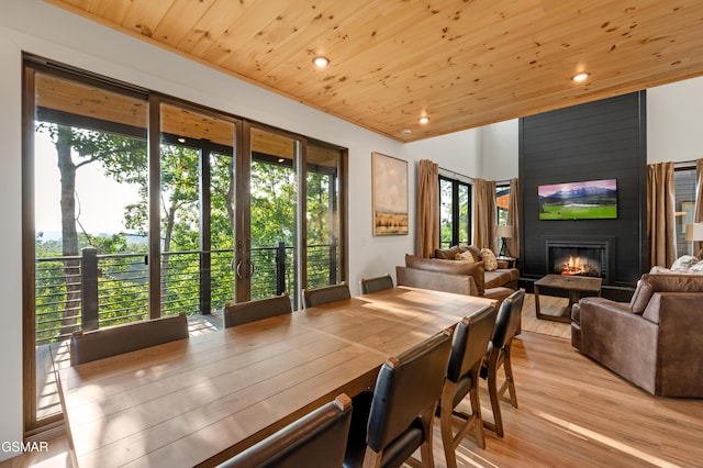 dining room with wood ceiling, recessed lighting, a large fireplace, and light wood finished floors