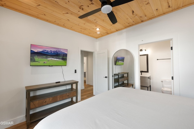 bedroom featuring wood ceiling, wood finished floors, ensuite bathroom, and baseboards