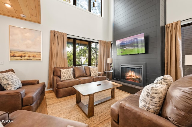 living room with a large fireplace, plenty of natural light, and a towering ceiling