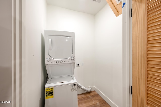 laundry room featuring estacked washer and dryer, wood finished floors, and baseboards