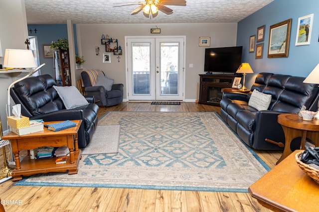 living room featuring a textured ceiling, french doors, light wood-type flooring, and ceiling fan