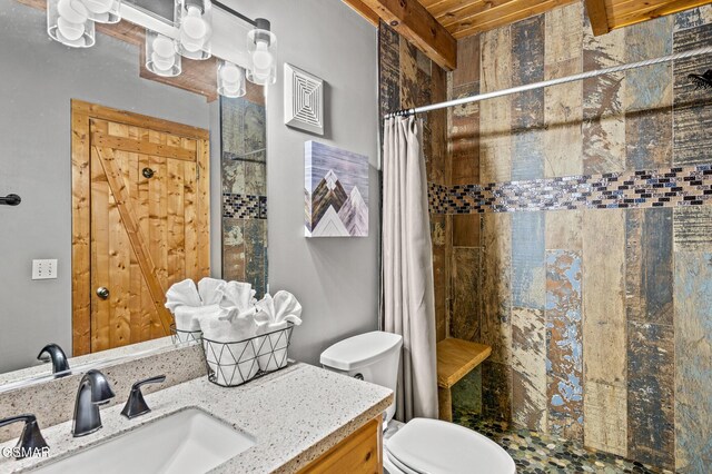 bathroom featuring beamed ceiling, vanity, toilet, and walk in shower