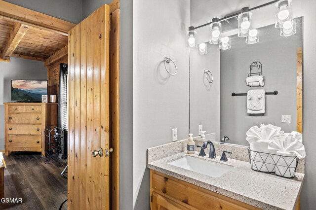 bathroom featuring beam ceiling, hardwood / wood-style floors, vanity, and wood ceiling