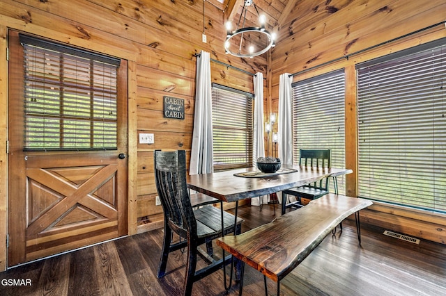 dining room with a chandelier, dark hardwood / wood-style flooring, lofted ceiling, and wood walls