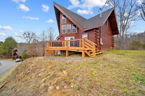 rear view of house featuring a yard, log siding, and a wooden deck