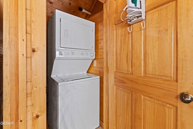 laundry room with stacked washing maching and dryer and wood walls