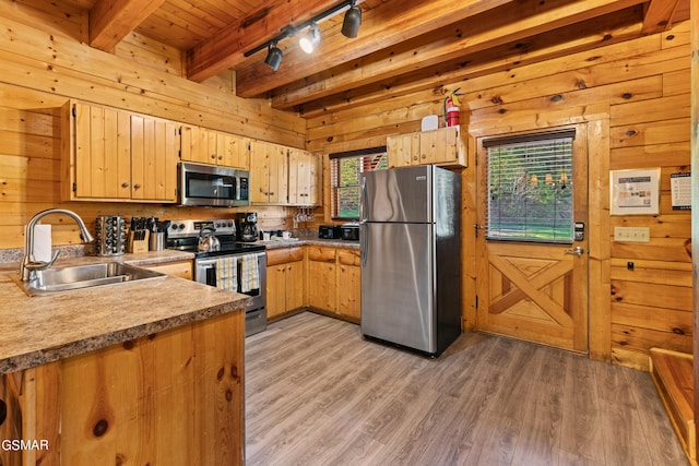 kitchen featuring sink, wood walls, and appliances with stainless steel finishes