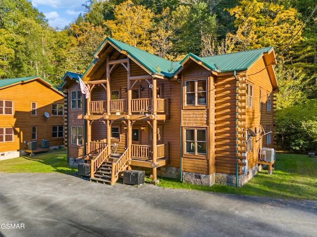 log cabin with a balcony, central AC unit, and covered porch