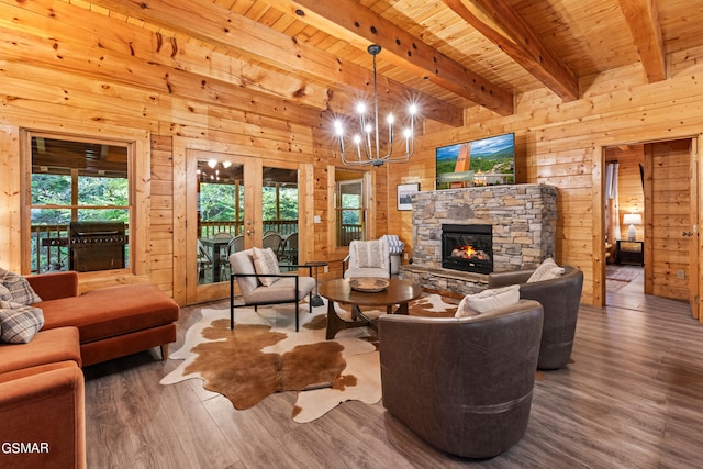 living room with beam ceiling, a fireplace, wooden ceiling, an inviting chandelier, and wooden walls