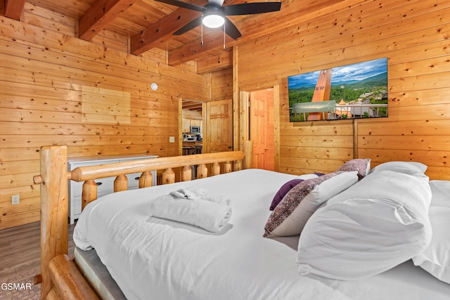 bedroom featuring beamed ceiling, hardwood / wood-style floors, wooden ceiling, ceiling fan, and wood walls